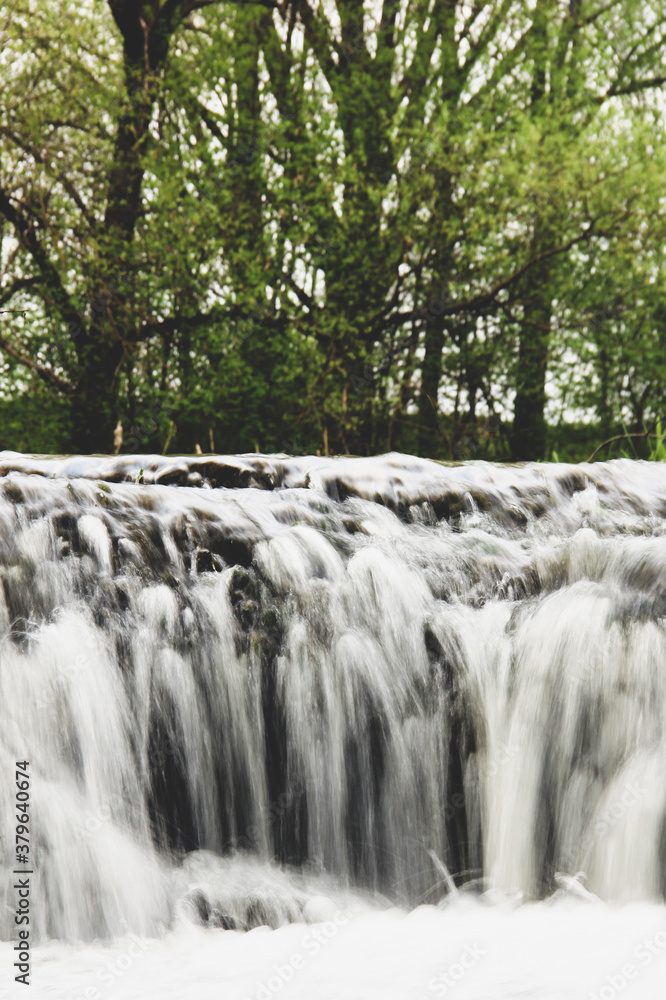 Beautiful waterfall in nature. River in the background of trees Beautiful waterfall in nature. River in the background of trees