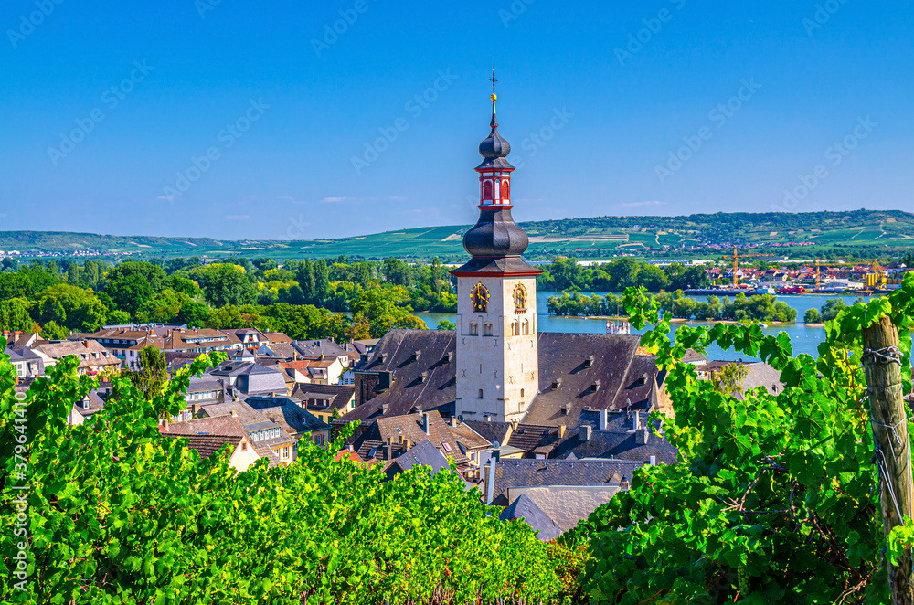 Aerial view of Rudesheim am Rhein historical town centre with clock tower spire of St. Jakobus catholic church and Rhine river, blue sky background, Rhineland-Palatinate and Hesse states, Germany
