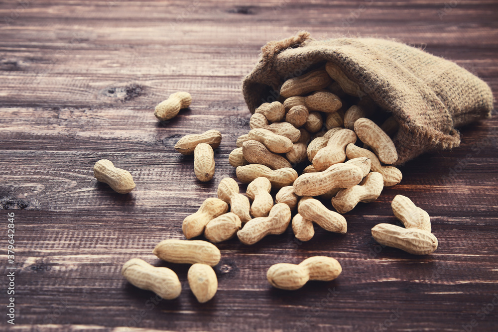 Peanuts in sackcloth on brown wooden table Peanuts in sackcloth on brown wooden table
