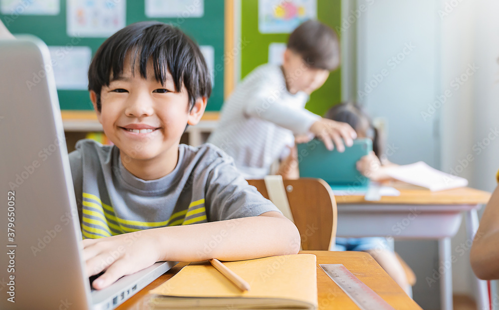 © paulaphoto - Portrait of Asian little boy using computer to learn lessons in elementary school. Student boy studying in primary. Children with gadgets. Education knowledge, technology internet network concept