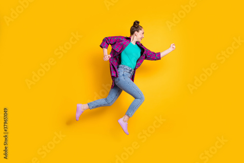 Full body profile photo of attractive teen lady jump high up run race marathon excited to win rushing competition wear casual plaid shirt sneakers jeans isolated yellow color background © deagreez