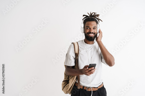 Photo of joyful african american guy using mobile phone and headphones