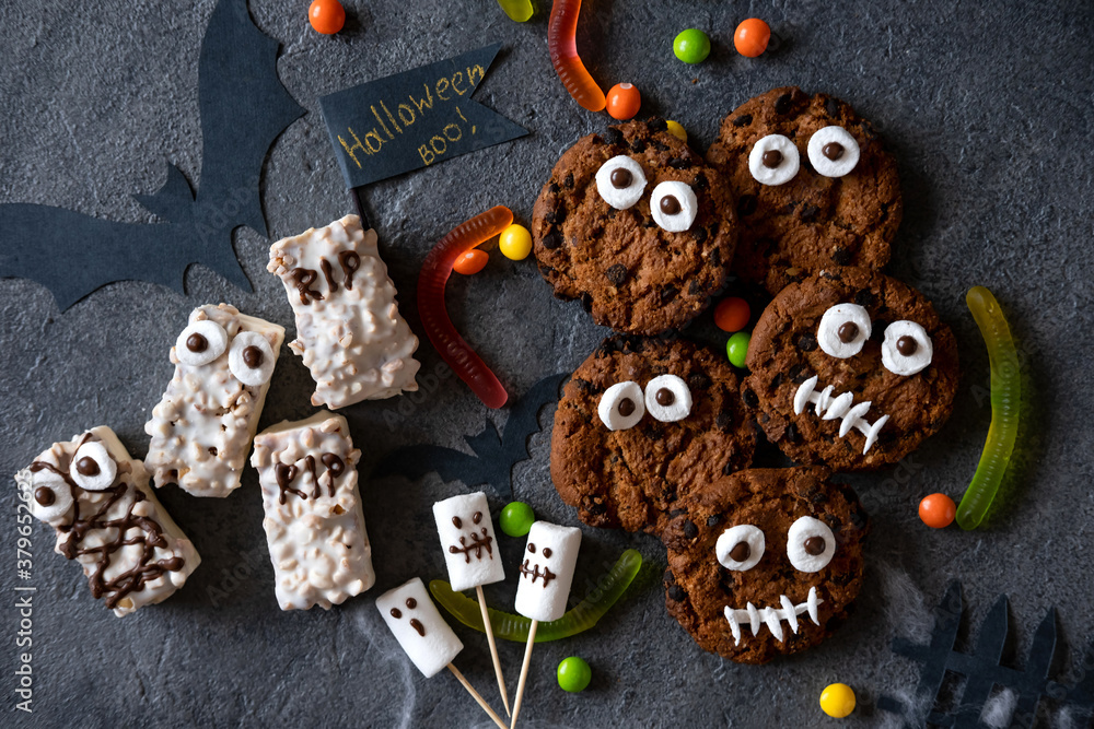 Modern Halloween background. Halloween candy bar: funny monsters made of biscuits with chocolate and ghosts marshmelow close-up on the table. Halloween party decoration. Trick or treat concept. Modern Halloween background. Halloween candy bar: funny monsters made of biscuits with chocolate and ghosts marshmelow close-up on the table. Halloween party decoration. Trick or treat concept.