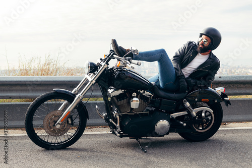 biker lying down on a motorcycle far from the city