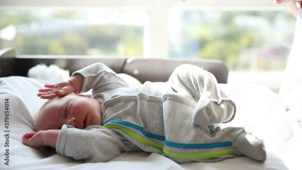 A little newborn baby fidgets in his sleeping in the baby cot A little newborn baby fidgets in his sleeping in the baby cot