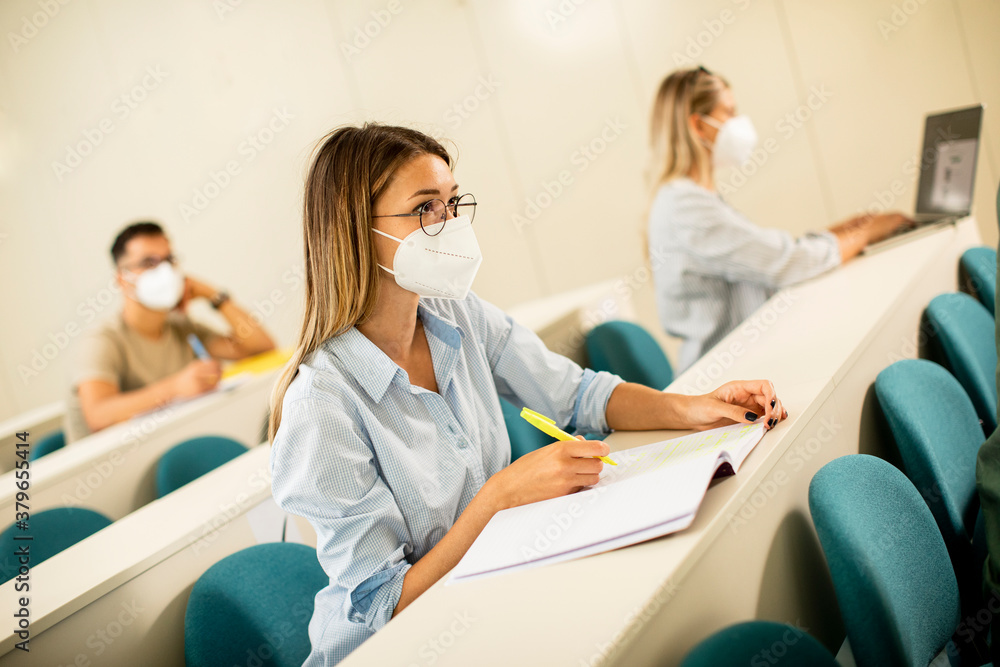 Obraz premium Female student wearing face protective medical mask for virus protection at lecture hall