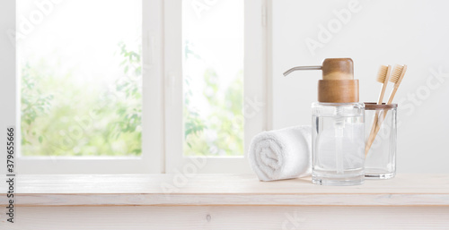 Wooden toothbrushes and eccentric soap dispenser against blurred window background