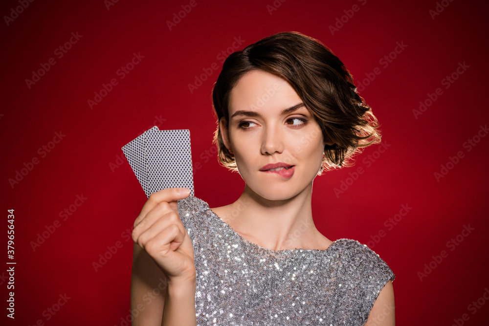 Closeup photo of attractive tricky lady professional casino player hold two cards risky gamer all in cheating bluffing bite lips wear shine dress isolated dark red gradient color background Closeup photo of attractive tricky lady professional casino player hold two cards risky gamer all in cheating bluffing bite lips wear shine dress isolated dark red gradient color background