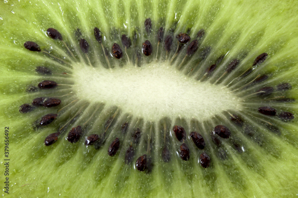 Antioxidants and Vitamin C rich foods and healthy exotic fruits concept with extreme macro close up on half cross section slice of fresh kiwi fruit with even lighting Antioxidants and Vitamin C rich foods and healthy exotic fruits concept with extreme macro close up on half cross section slice of fresh kiwi fruit with even lighting