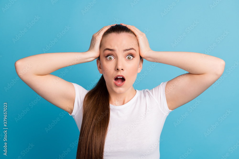 Portrait of astonished panic nervous girl hear horrible news impressed touch hands head wear good look clothes isolated over blue color background Portrait of astonished panic nervous girl hear horrible news impressed touch hands head wear good look clothes isolated over blue color background