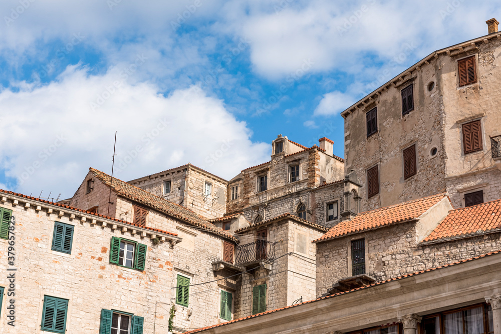 Old medieval buildings against a blue sky with clouds in Sibenik, Croatia