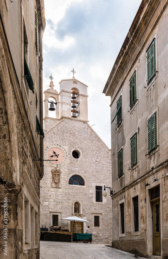 Medieval church with bell tower, clocks and cross in Sibenik; Croatia