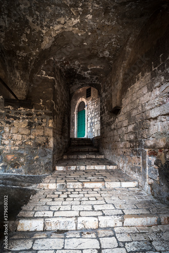 Fototapeta Naklejka Na Ścianę i Meble -  Medieval narrow street with a green door in Sibenik, Croatia