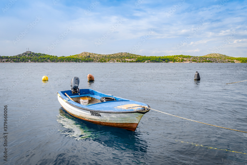 Wooden boat on a leash near the sea shore in Sibenik, Croatia Wooden boat on a leash near the sea shore in Sibenik, Croatia