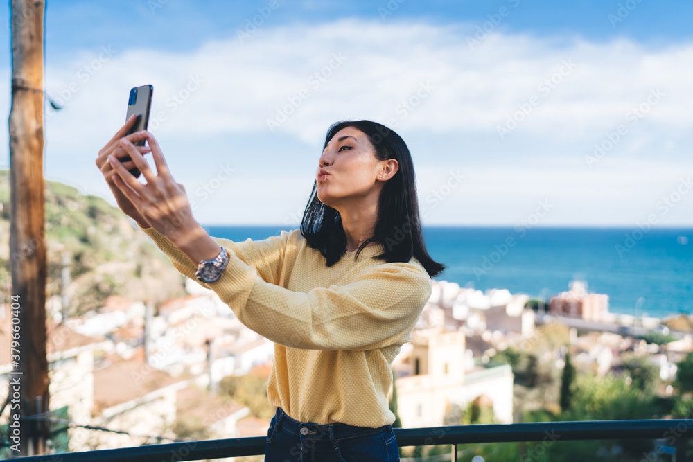 Attractive Asian hipster tourist making duck face grimace during travel vacations, beautiful teenage vlogger shooting video showing kiss to front camera during sightseeing to overlooking area Attractive Asian hipster tourist making duck face grimace during travel vacations, beautiful teenage vlogger shooting video showing kiss to front camera during sightseeing to overlooking area