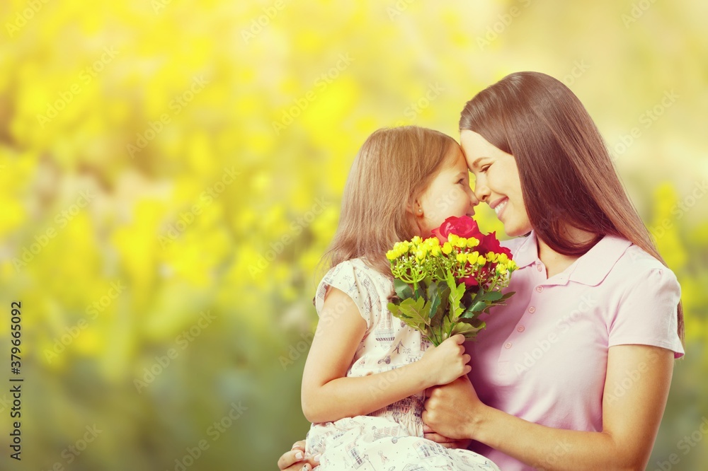Fototapeta premium Mother and daughter with bouquet of flowers on blurred background.