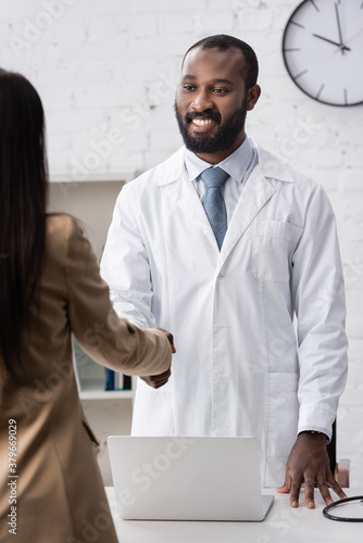 Selective focus of african american doctor standing and looking at patient photo