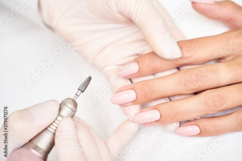 Beautiful salon procedure with pink manicure on towel background. For decoration design. Machine healthcare. Woman body care. Spa treatment. White background. Nail brush and polish.