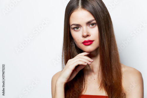 Girl with bare shoulders Beautiful face hand near the chin red lips 