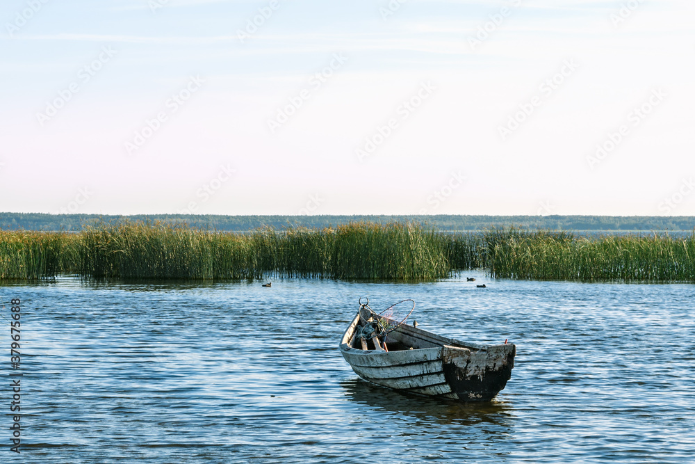 Naklejka premium Lonely wooden rowing fishing boat on Lake Drivyaty at sunset. Braslav lakes. Belarus