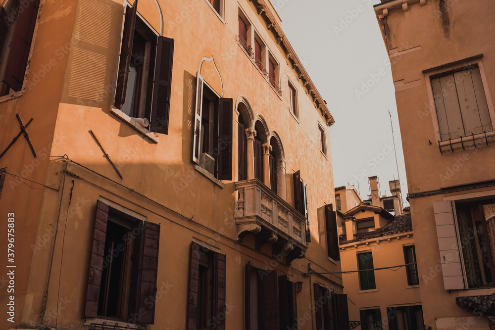 Architecture and landmarks of Venice, Italy. Ancient brick and beige buildings, narrow streets between the houses, tiled roofs.