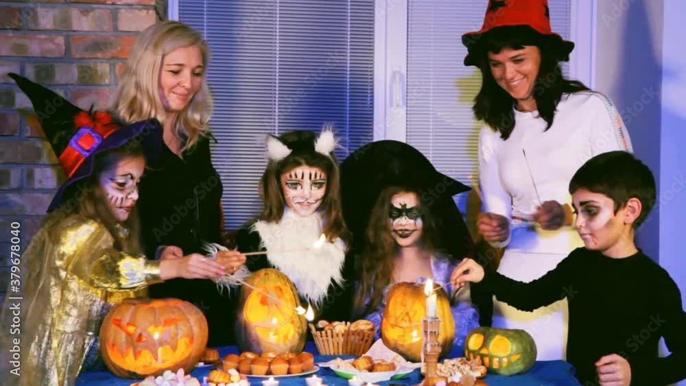 A group of children and women decorate the table with Halloween treat A group of children and women decorate the table with Halloween treat