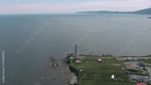 Blue Calm Water Of Saint Lawrence River With Cap Des Rosier Lighthouse Near The Village In Gaspe Peninsula, Quebec Canada. - Aerial Drone Shot photo