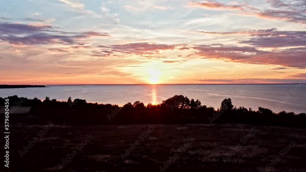 Moving aerial of sun setting into sea with amazing cloudscape Moving aerial of sun setting into sea with amazing cloudscape