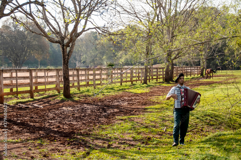 Young man playing harmonica on a ranch with horses in the background Young man playing harmonica on a ranch with horses in the background