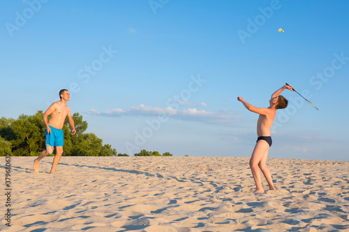 Happy family have fun playing beach badminton on summer vacation on a sunny day. Outdoor sports games. Active healthy lifestyle concept.