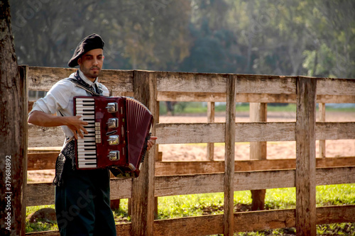 Quadro su tela Young man playing the accordion in profile on a horse ranch.