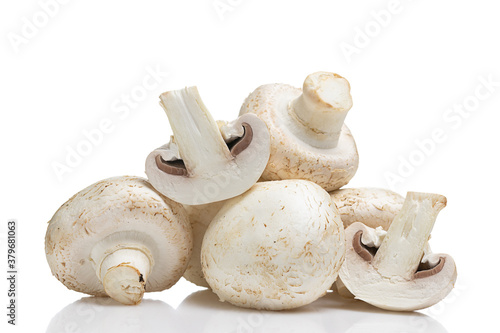 Close up of whole and halved champignons on smooth reflective surface. Button mushrooms isolated on white background