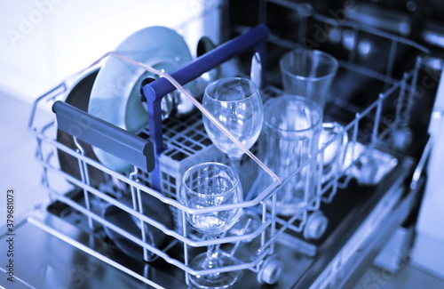 Open dishwasher with clean dishes background