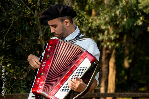 Foto Gaucho boy with typical costumes playing the harmonica outdoors.