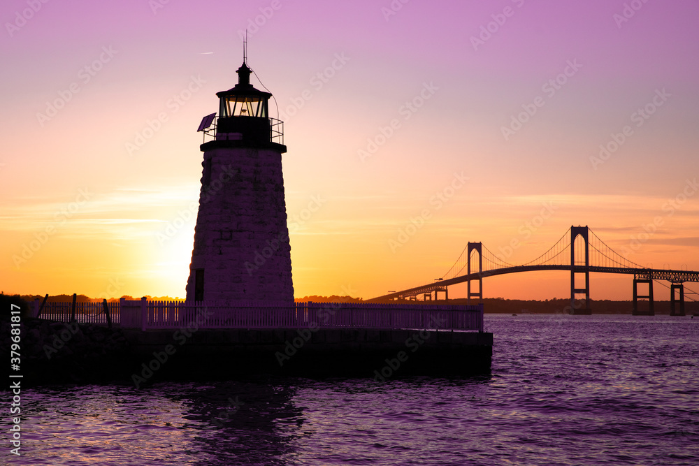 Sunset over Newport Harbor Lighthouse with bridge and colorful sky Sunset over Newport Harbor Lighthouse with bridge and colorful sky