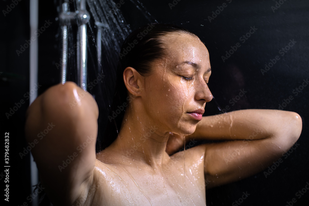 Pretty girl washing her body taking shower closing eyes with drops of water running down her wet skin.