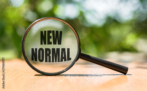 Magnifying glass with message: NEW NORMAL. Concept Search new normal photo