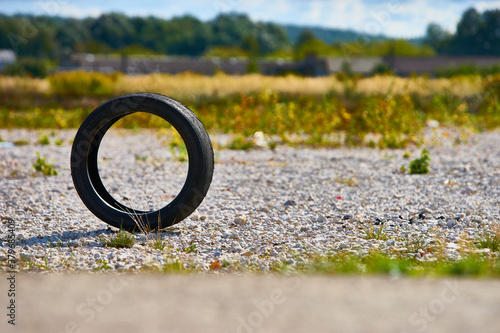 a used car wheel stands on an edge. you can see the side of the road through it. color nature