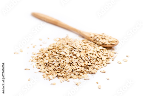 A full wooden spoon behind a pile of oat flakes