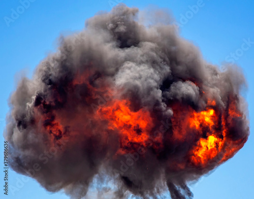 Ball of smoke and fire from mutions explosion against blue sky