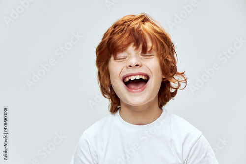 funny red-haired boy with closed eyes with wide open mouth smile cropped view 