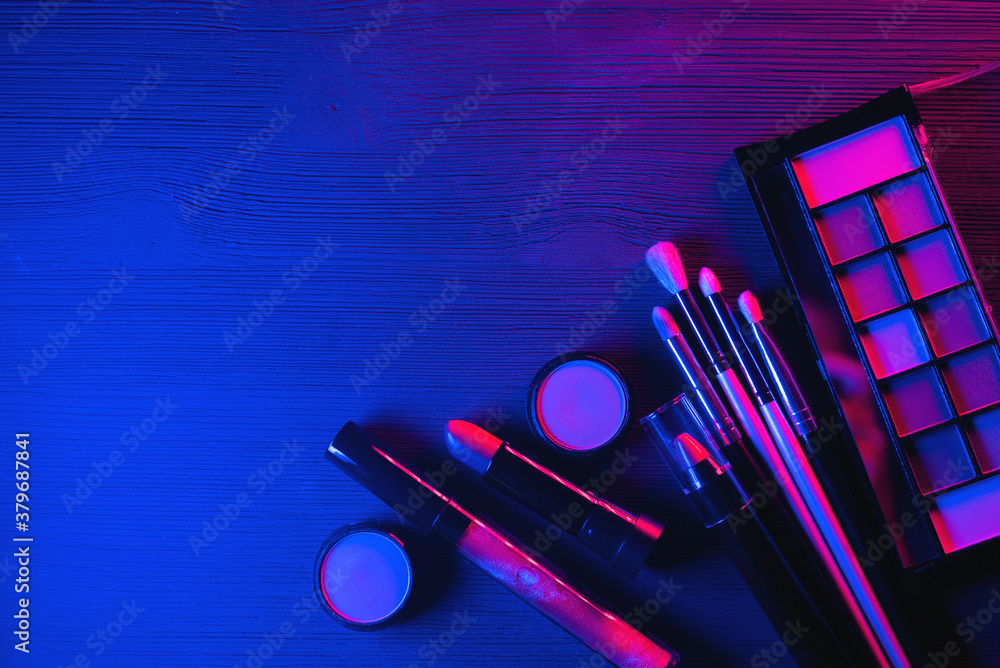Eyeshadows palette, lipstick and makeup brushes in the neon lights