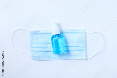 Medical face mask and disinfectant in spray bottle. White background.
