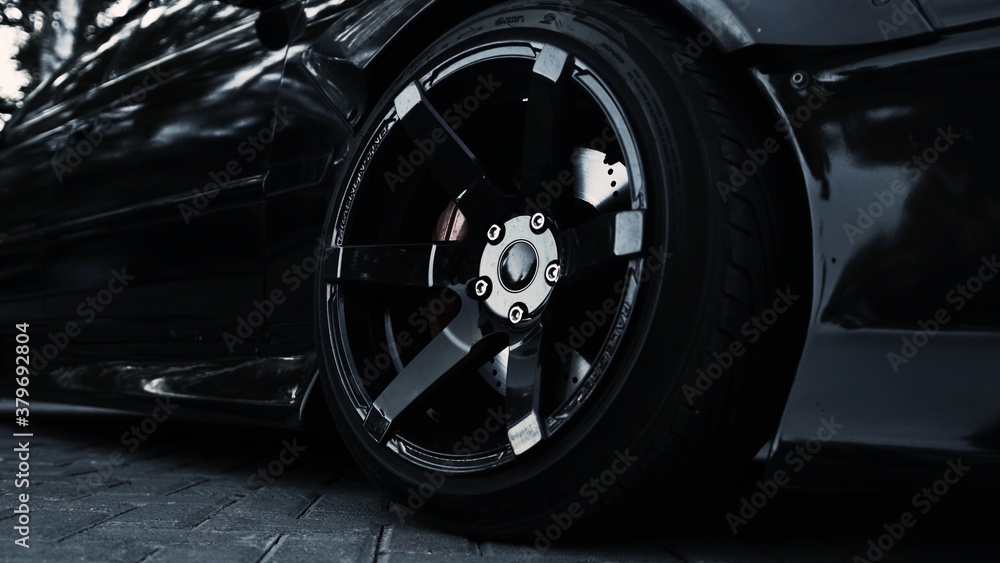 Side view of a black sports car and a stylish wheel