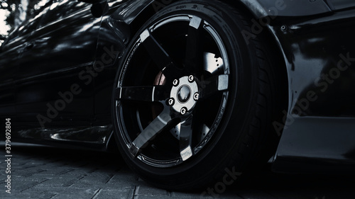 Side view of a black sports car and a stylish wheel © Alexey