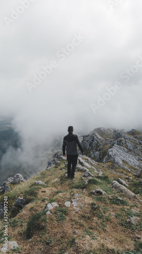 Hombre de espaldas realizando senderismo en las montañas del Parque Natural de Aizkorri-Aratz en el País Vasco en un día de nubes bajas