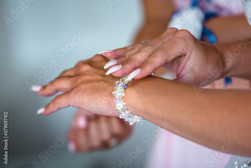 Bridesmaid is helping bride to put on bracelet  moring wedding preparations