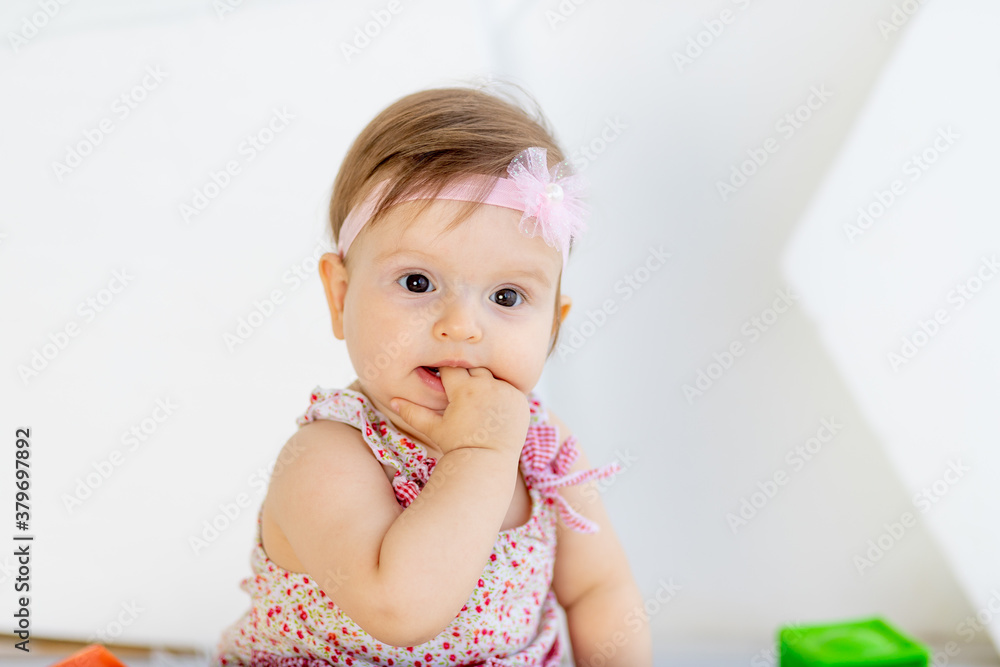 beautiful portrait of little baby girl sucking finger in red clothes