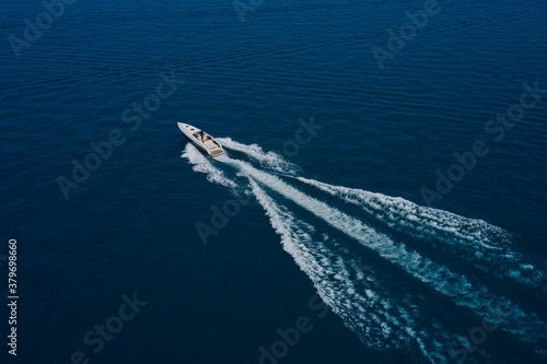 Drone view of a boat  the blue clear waters. Drone view of a boat sailing. Large speed boat moving at high speed side view. Top view of a white boat sailing to the blue sea.