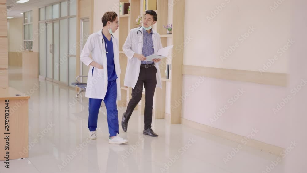 Young asian doctor walk talk and discuss together feeling relax in private ward with concept morning round ward at hallway corridor hospital. Routine health care work at clinic. Young asian doctor walk talk and discuss together feeling relax in private ward with concept morning round ward at hallway corridor hospital. Routine health care work at clinic.